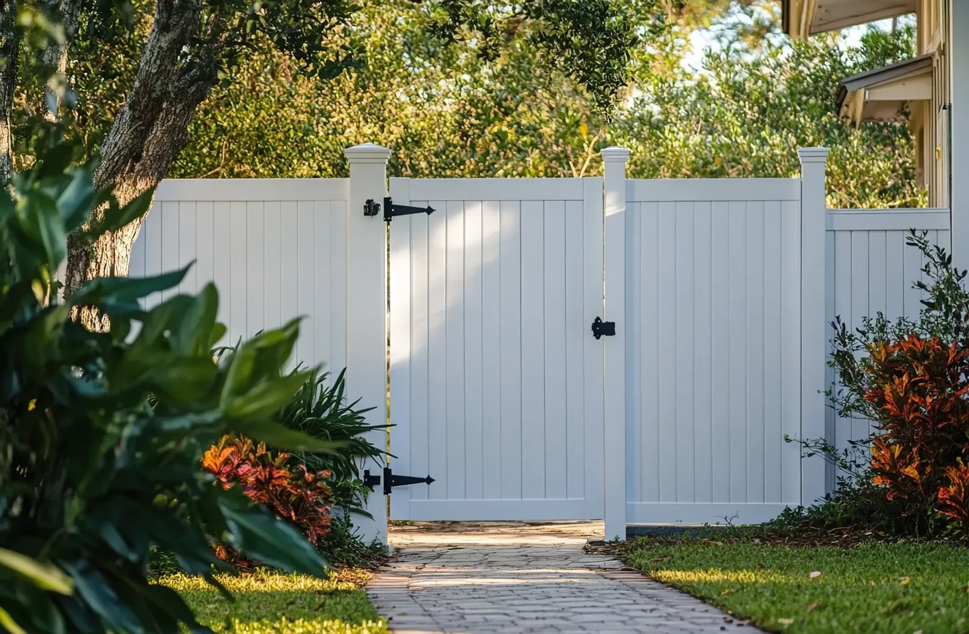 White vinyl privacy fence gate with black hardware on residential pathway