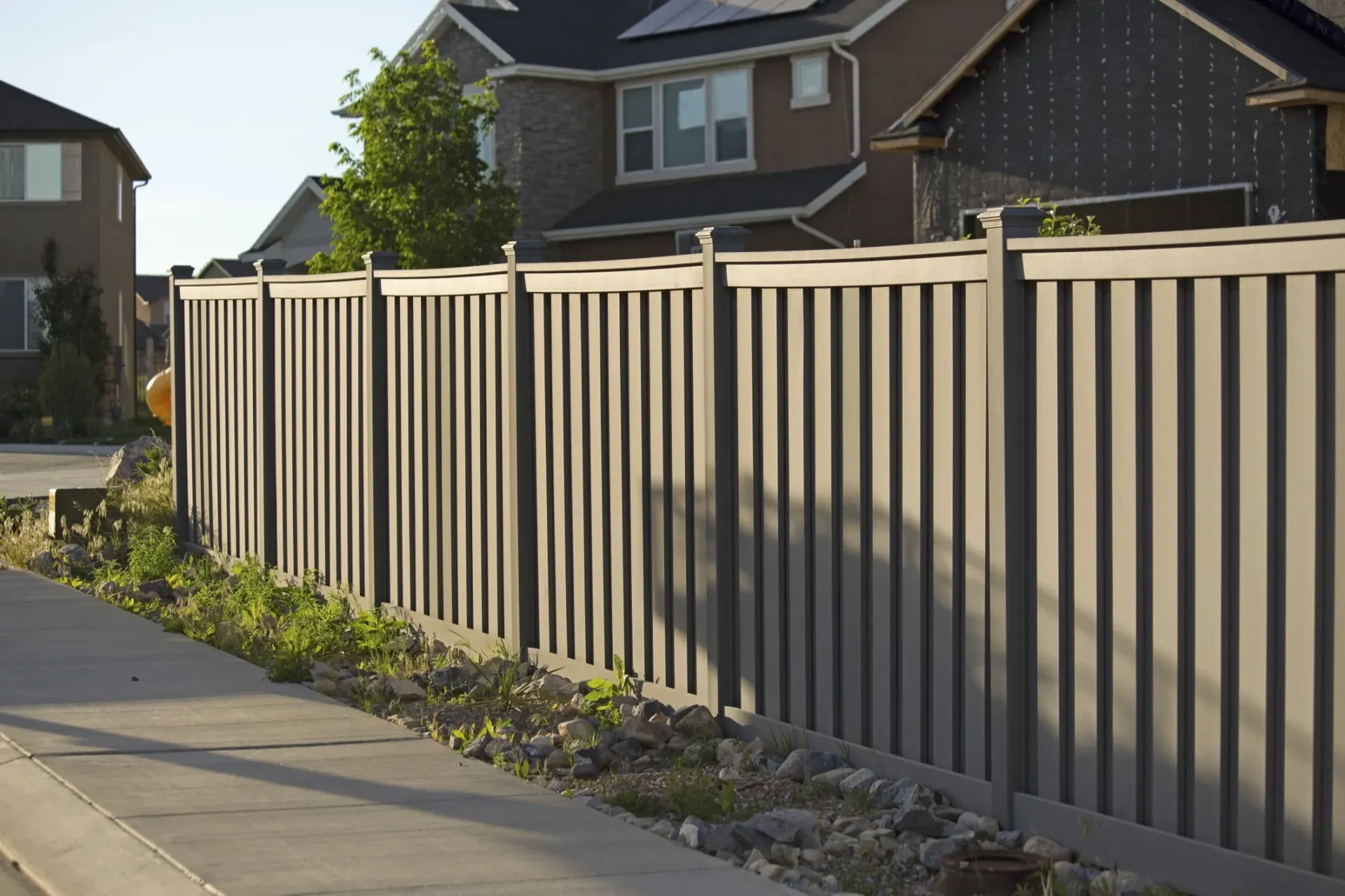 Cream-colored vinyl fence with vertical slats along residential driveway