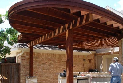 Wooden pergola structure attached to brick house with lattice panels and exposed beams